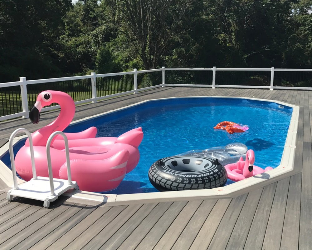 A swimming pool with a pink flamingo float and a black inner tube float.